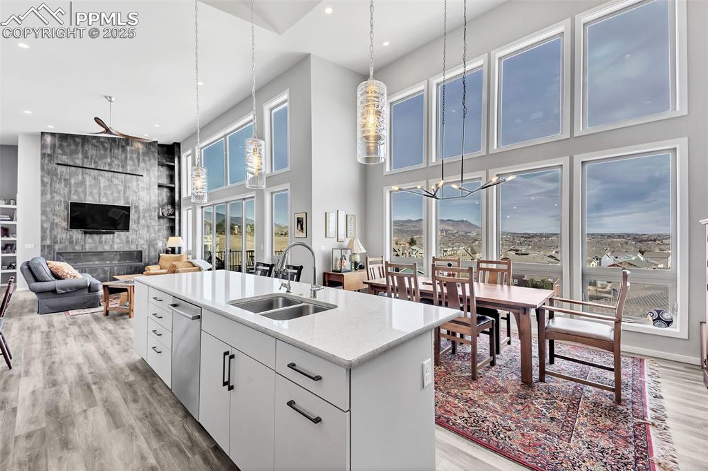414 Eclipse Drive Colorado Springs, CO 80905 - Photo 7 of 50 Kitchen with a sink, a chandelier, white cabinetry, light wood-style flooring, and a kitchen island with sink