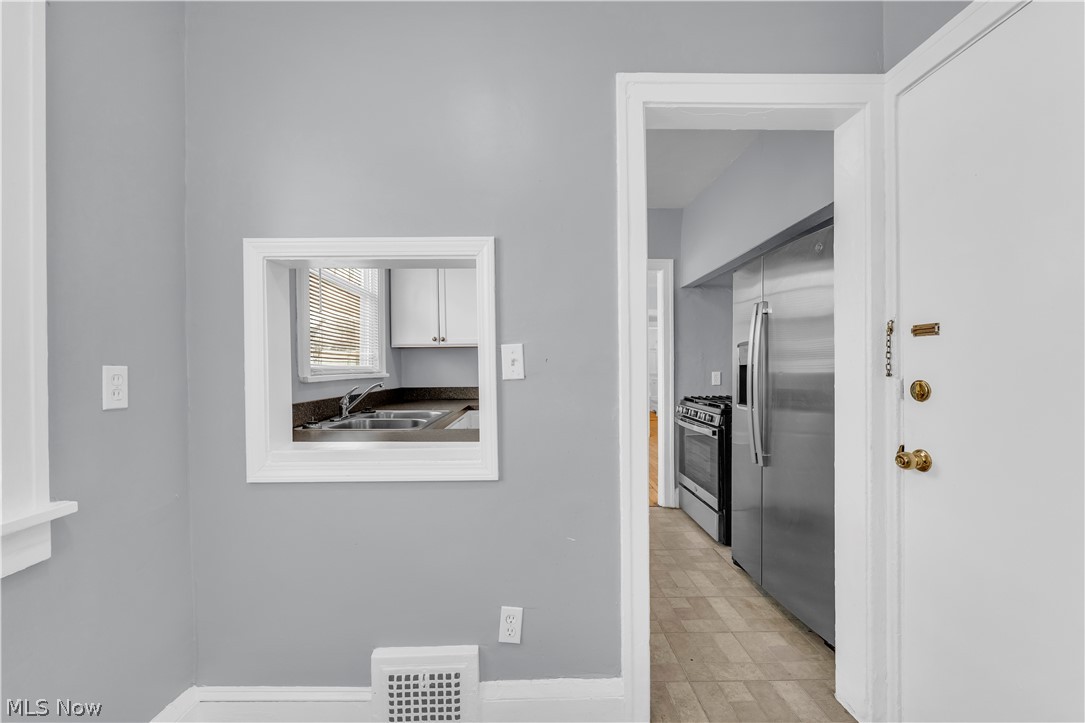 3318 Milverton Road, Unit 1/DN Shaker Heights, OH 44120 - Photo 8 of 21 Kitchen with a pass-through window, providing a view of the sink, upper white cabinets, and a window with blinds