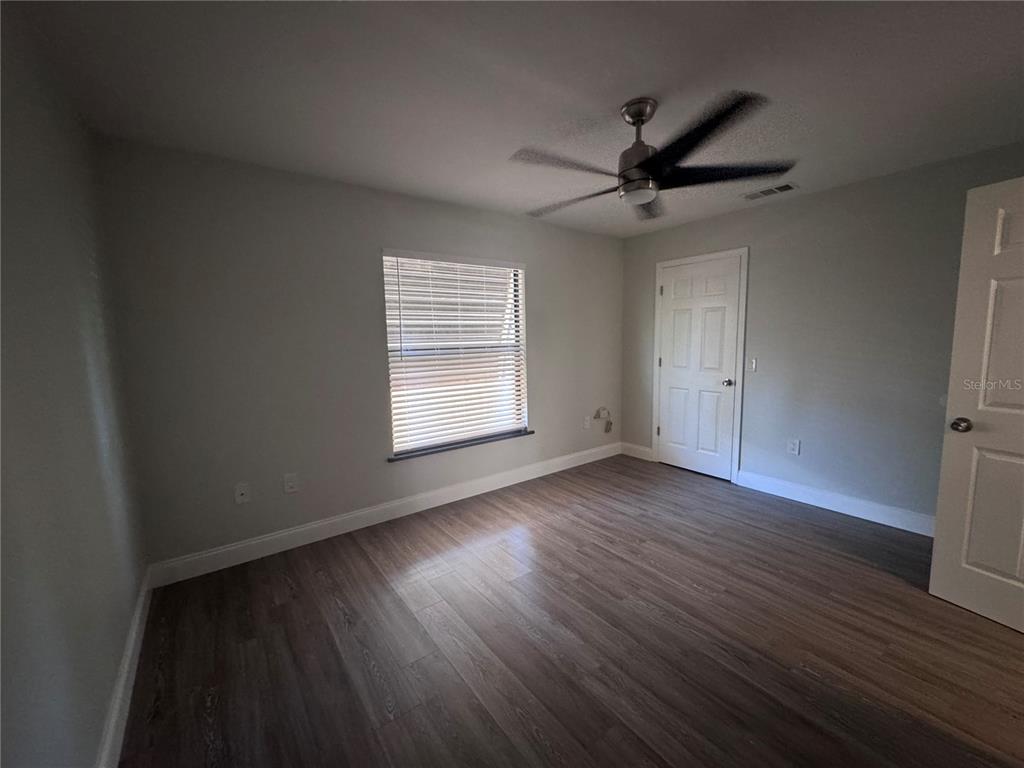 1755 Highland Road Osprey, FL 34229 - Photo 24 of 31 an empty room with wooden floor a ceiling fan and windows