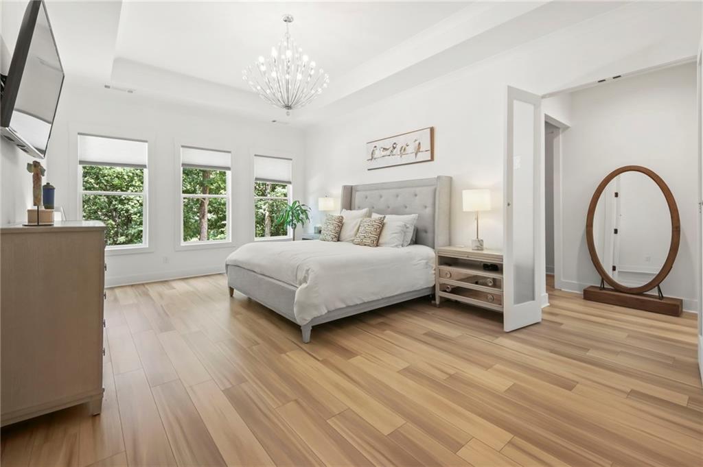 6014 Warpath Road Flowery Branch, GA 30542 - Photo 16 of 36 a bedroom with a bed a mirror and a large window