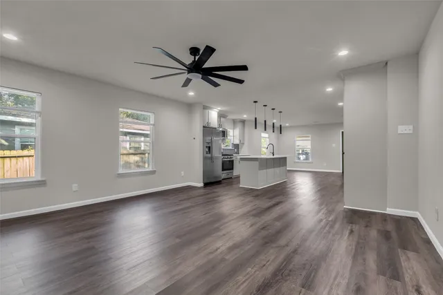a view of a kitchen with a dishwasher a kitchen island hardwood floor and a window