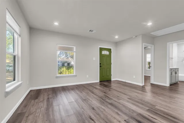 a view of an empty room with wooden floor and a window