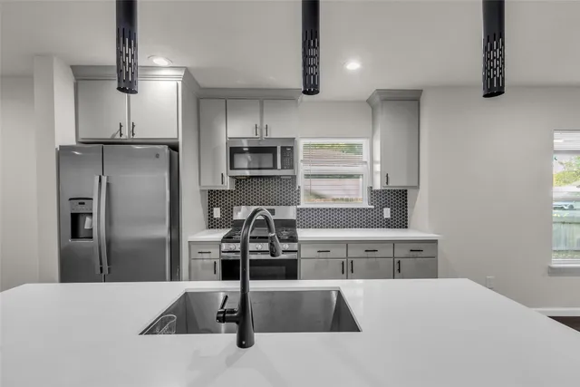 a kitchen with stainless steel appliances kitchen island a refrigerator sink and cabinets