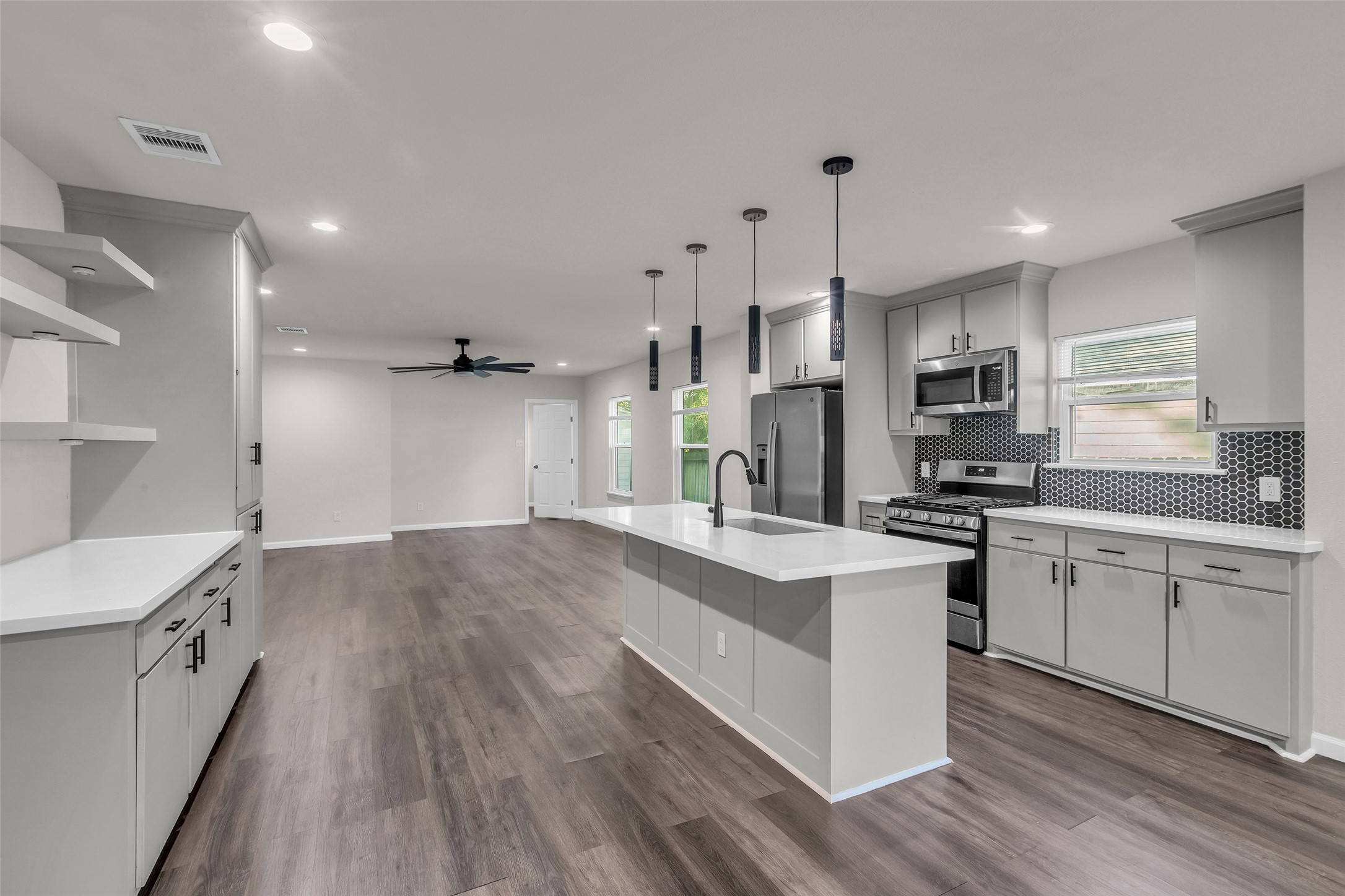116 Gans Street Houston, TX 77029 - Photo 5 of 25 a large kitchen with granite countertop a large stove a sink dishwasher a refrigerator and white cabinets with wooden floor