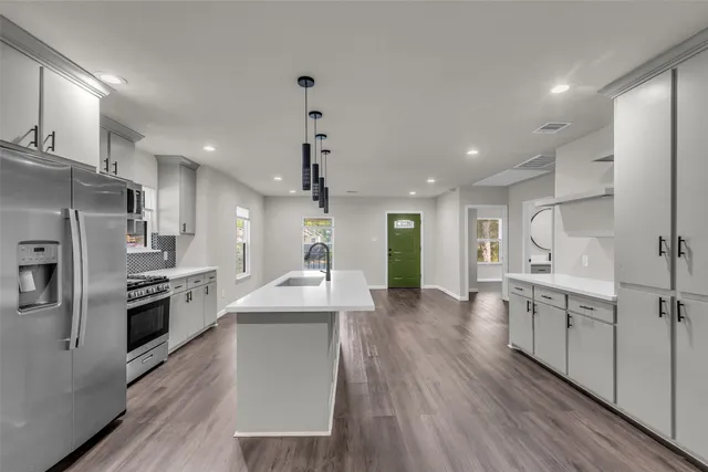 a large kitchen with stainless steel appliances kitchen island a large counter top and wooden floors