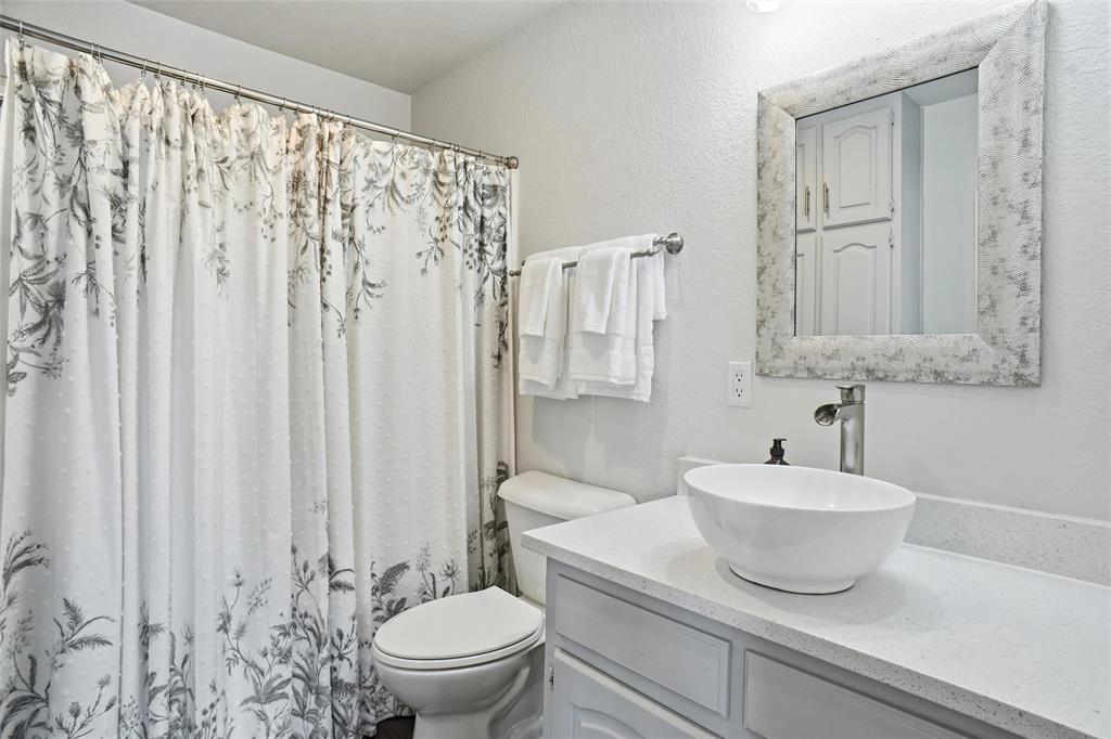 9501 Confederate Park Road Lakeside, TX 76135 - Photo 20 of 33 a bathroom with a granite countertop sink a toilet and a mirror