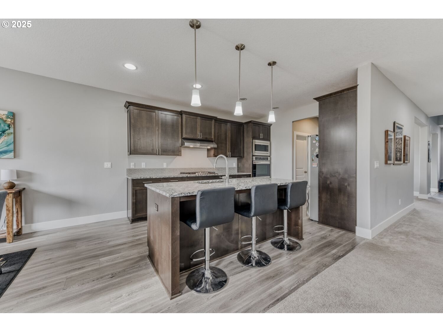 1561 Southwest Stringtown Road Forest Grove, OR 97116 - Photo 12 of 48 a kitchen with kitchen island granite countertop a sink cabinets a refrigerator and wooden floor