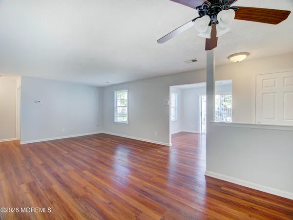 a view of an empty room with window and wooden floor