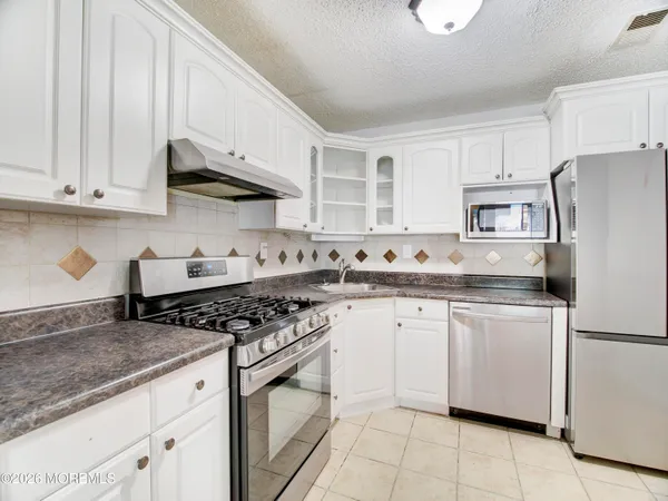 a kitchen with granite countertop white cabinets and white appliances
