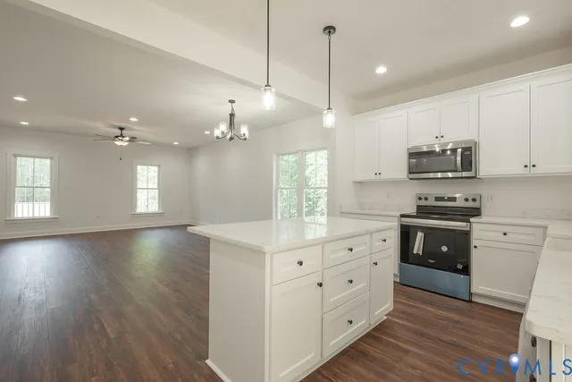 a kitchen with stainless steel appliances granite countertop a sink a stove a refrigerator and white cabinets with wooden floor