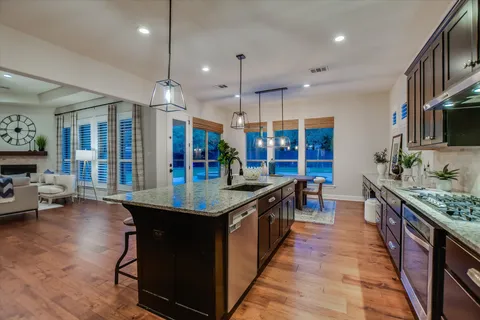 a kitchen with stainless steel appliances granite countertop a stove and a large island with wooden floor