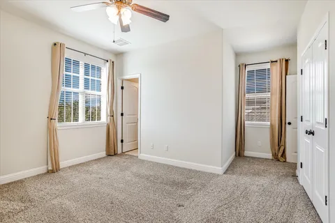 an empty room with windows closet and chandelier fan