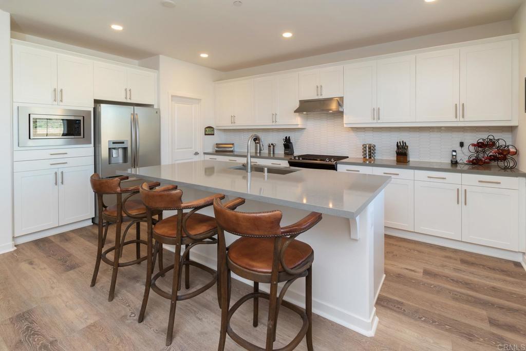 9056 Hightail Drive Santee, CA 92071 - Photo 8 of 73 a kitchen with stainless steel appliances granite countertop a table chairs microwave and sink