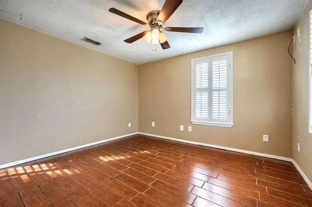 a view of an empty room with window and a chandelier fan