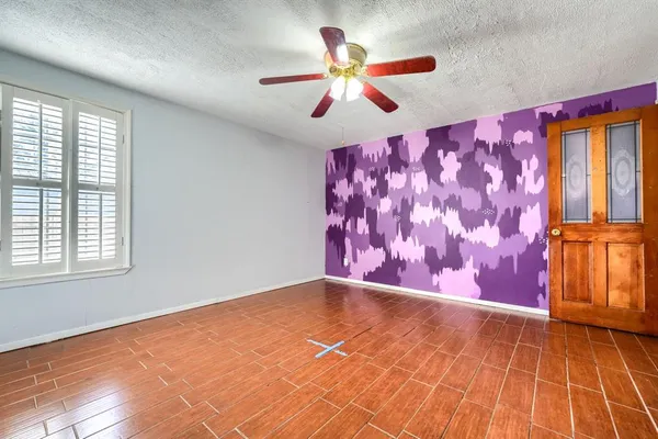 a view of an empty room with window and chandelier fan
