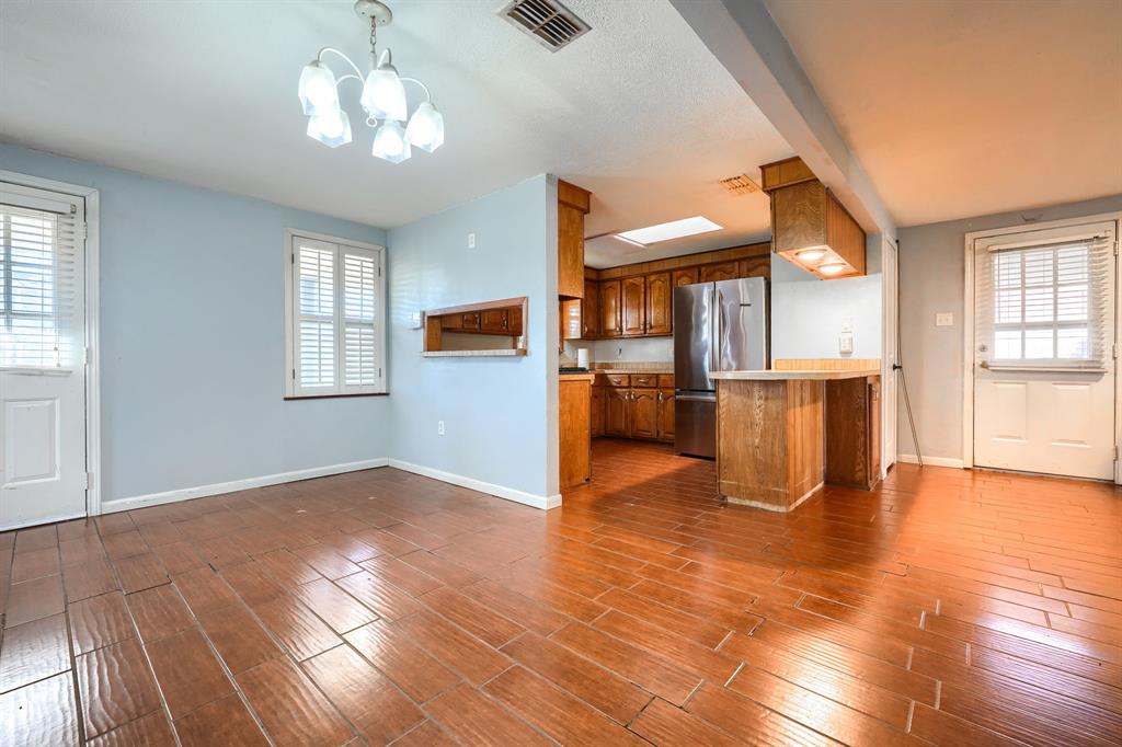 2112 Mangum Street Commerce, TX 75428 - Photo 5 of 19 an empty room with wooden floor a chandelier fan and windows
