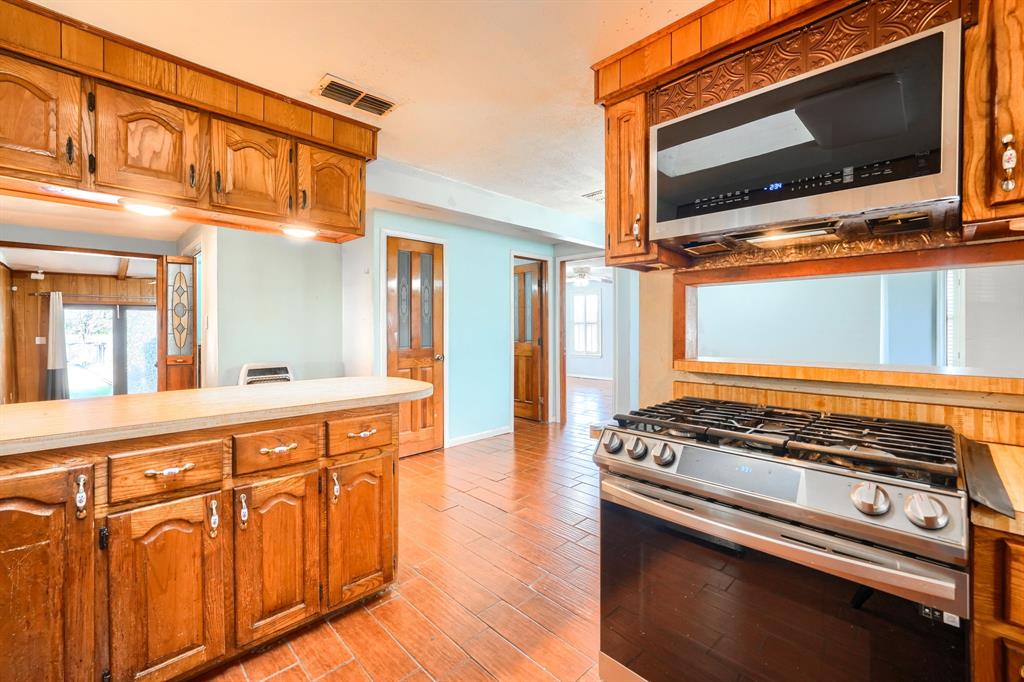 2112 Mangum Street Commerce, TX 75428 - Photo 8 of 19 a view of a kitchen with stainless steel appliances granite countertop a stove and a microwave