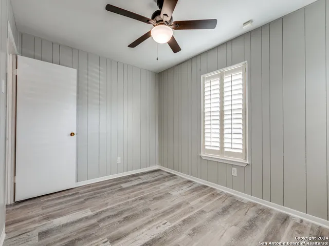 a view of empty room with wooden floor and fan