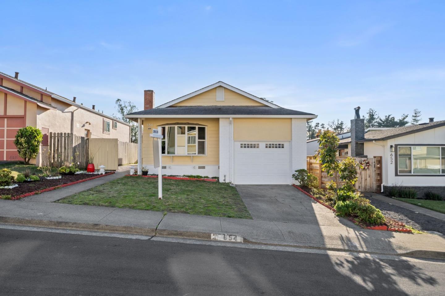 654 Foothill Drive Pacifica, CA 94044 - Photo 2 of 24 a front view of a house with a yard and garage