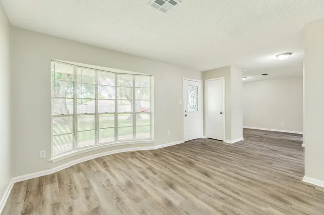 an empty room with wooden floor and windows