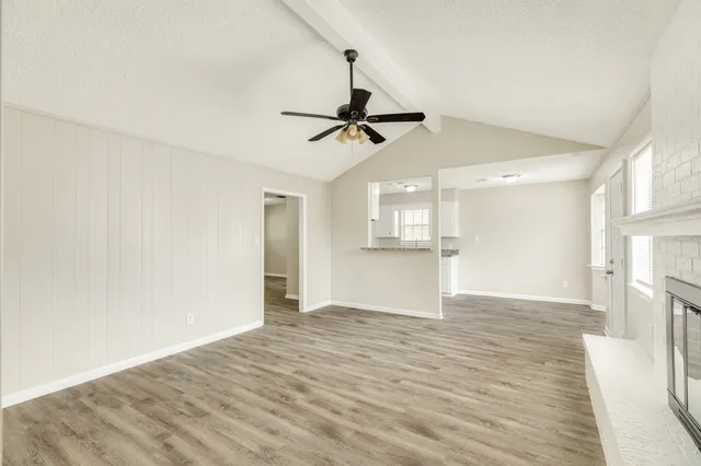 a view of empty room with wooden floor and ceiling fan
