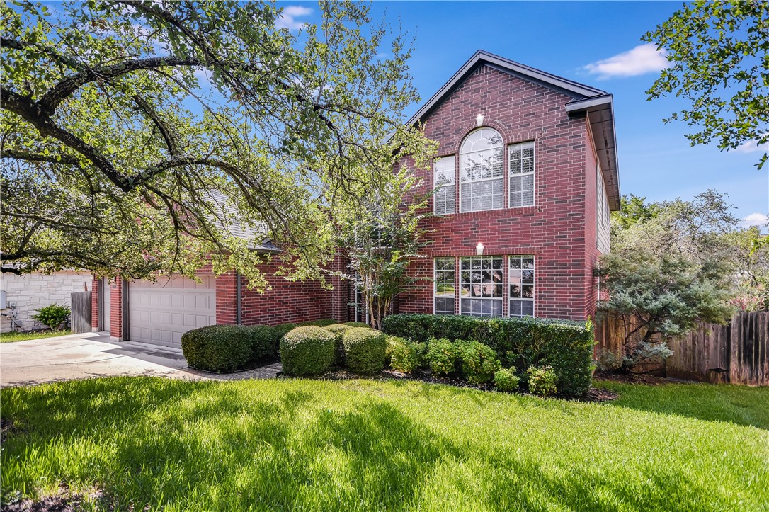 View of front facade with brick siding, driveway, and an attached garage
