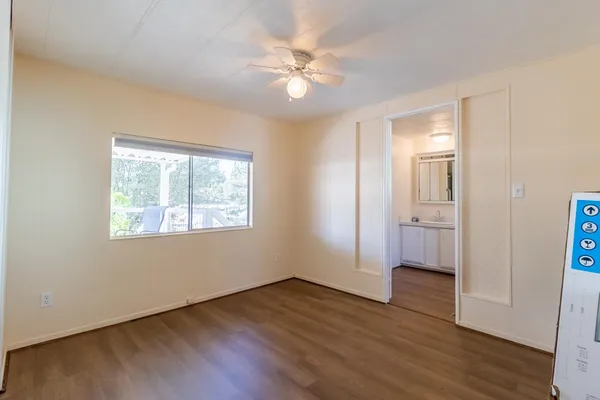 a view of an empty room with wooden floor and a window