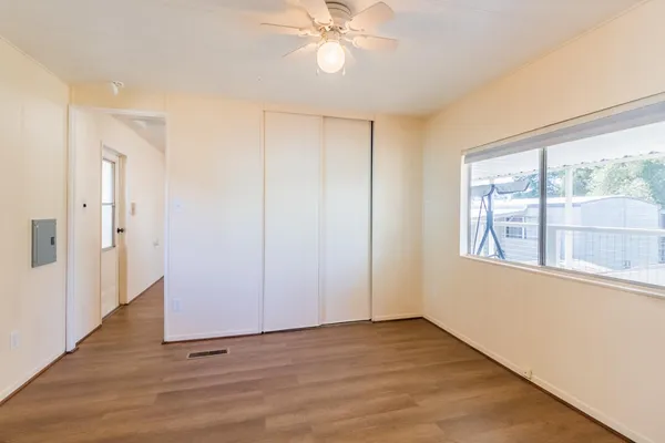 a view of an empty room with wooden floor and a window