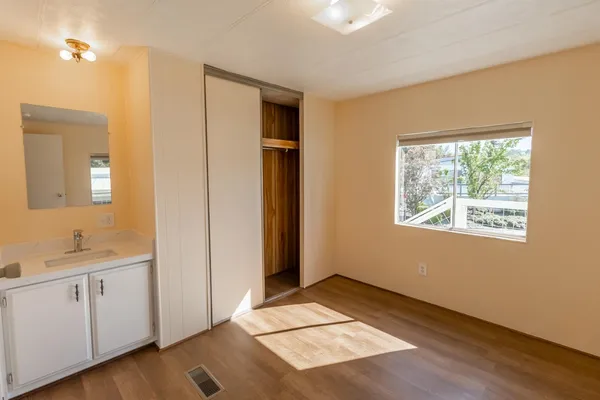 a view of an empty room with window and wooden floor