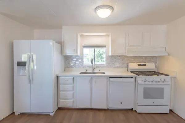 a kitchen with white cabinets and white appliances