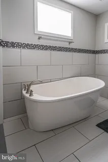 a white bath tub sitting next to a white wooden cabinet