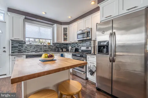 a kitchen with stainless steel appliances a sink a stove a refrigerator a counter top space and cabinets