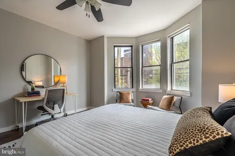 a bedroom with a bed a large window and a chandelier