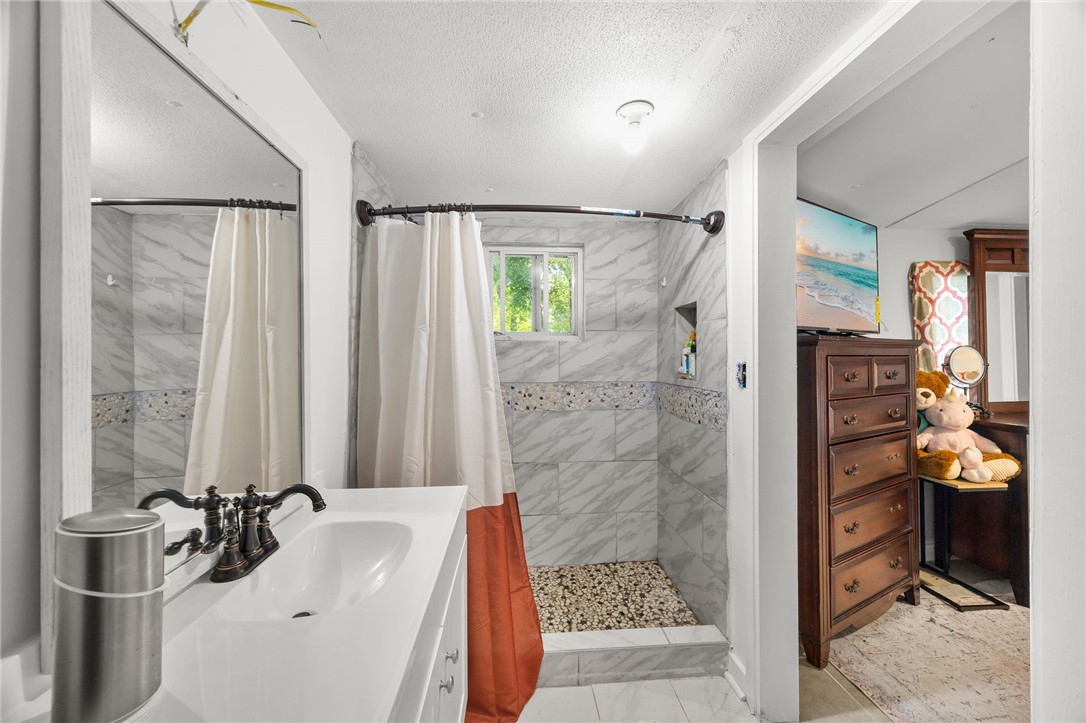 217 Old River Road Pelzer, SC 29669 - Photo 16 of 30 This bathroom features a contemporary shower with stone flooring, complemented by a sleek vanity and ample natural light.