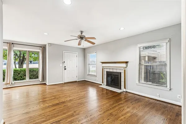 a view of an empty room with wooden floor fireplace and a window