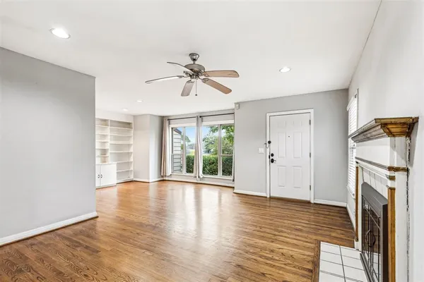 a view of an empty room with a window and wooden floor