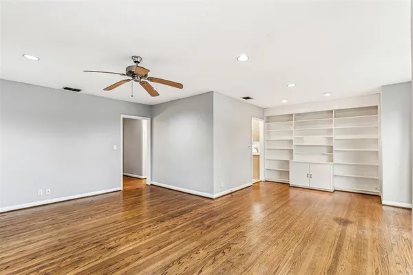 a view of an empty room with a window and wooden floor