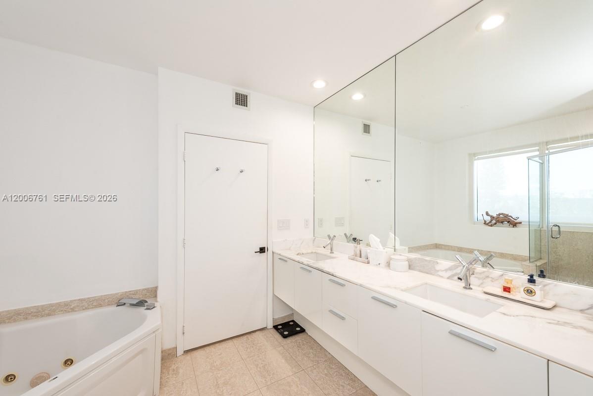 400 Alton Road, Unit TH1A Miami Beach, FL 33139 - Photo 20 of 32 a bathroom with a double vanity sink a mirror and a bathtub