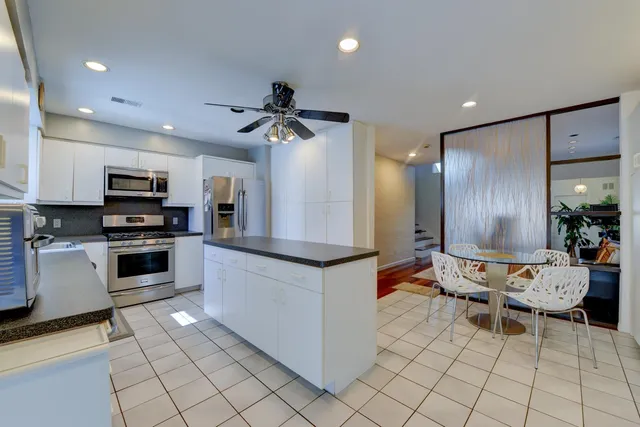 a kitchen with stainless steel appliances kitchen island granite countertop a refrigerator and a stove top oven