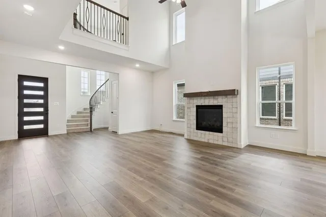 an empty room with wooden floor fireplace and windows