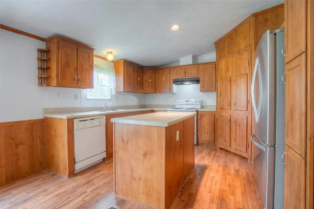 a kitchen with stainless steel appliances granite countertop a refrigerator a sink dishwasher a stove with wooden cabinets and floor