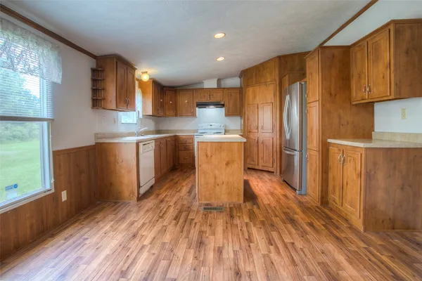 a kitchen with stainless steel appliances a refrigerator a sink dishwasher and wooden cabinets with wooden floor