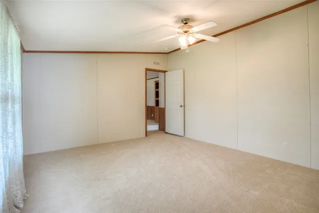 an empty room with a ceiling fan and a window