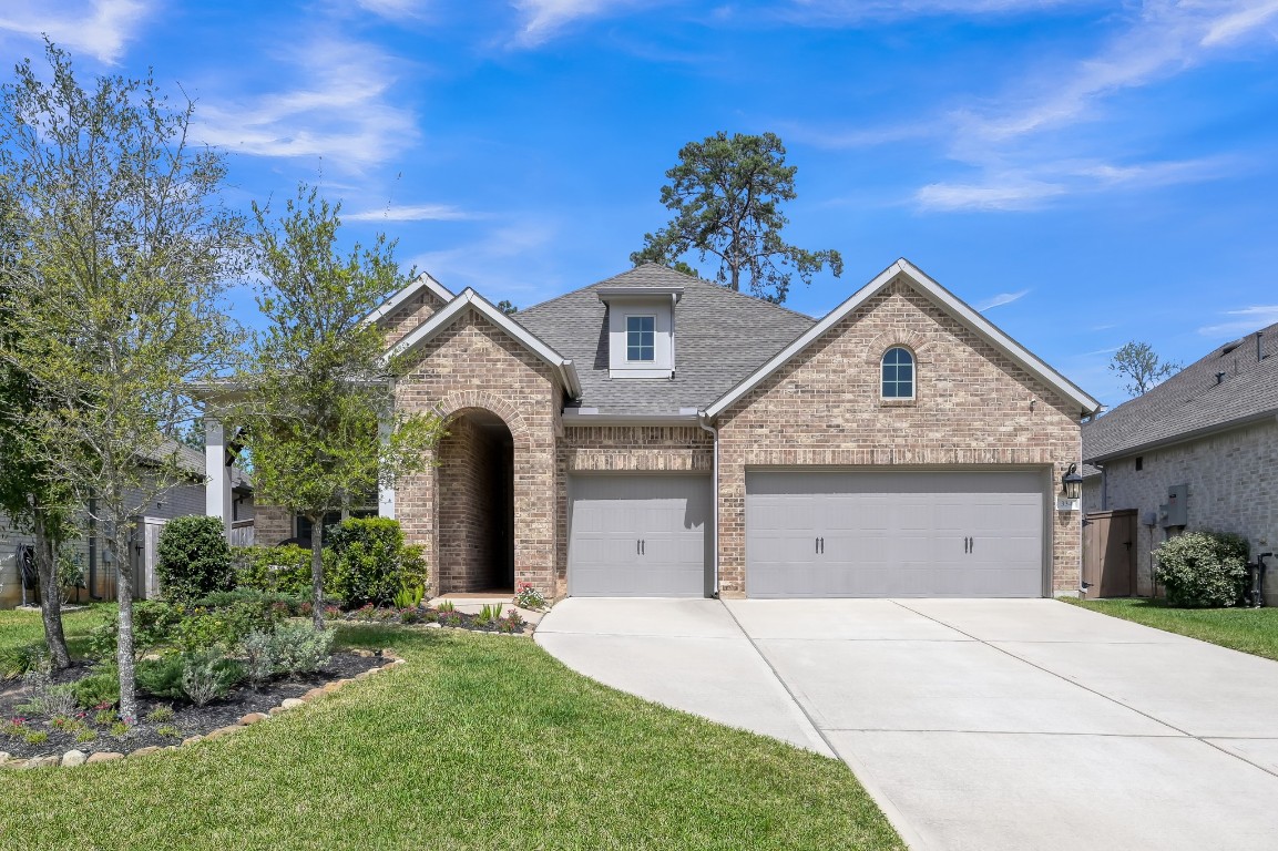 David Weekley 1.5-story home built in 2021 featuring beautiful brick elevation, inviting arched entry, and exceptional curb appeal with a spacious 3-car garage.