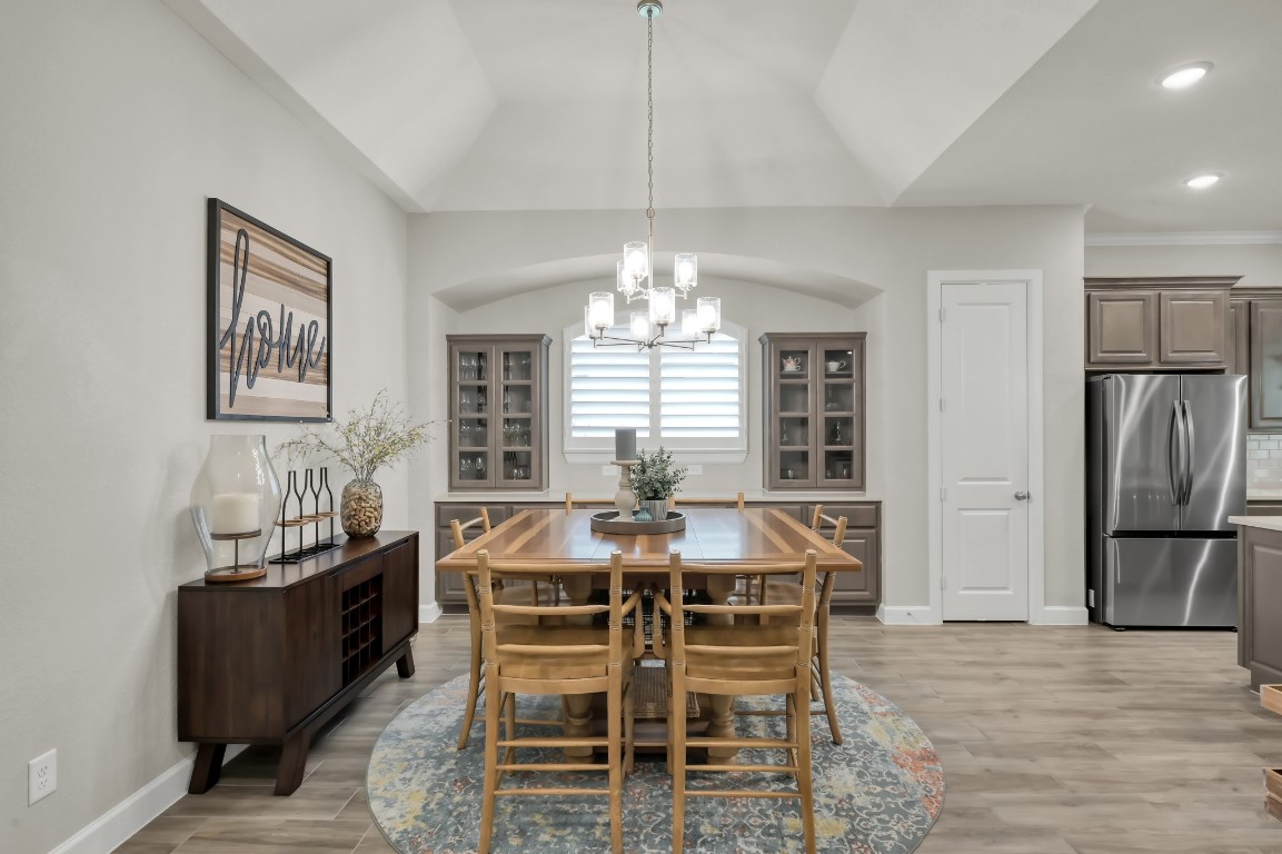 334 Torrey Bloom Loop Conroe, TX 77304 - Photo 10 of 46 Elegant dining space with tray ceiling, statement chandelier, and custom built-ins, seamlessly connected to the kitchen for effortless entertaining.