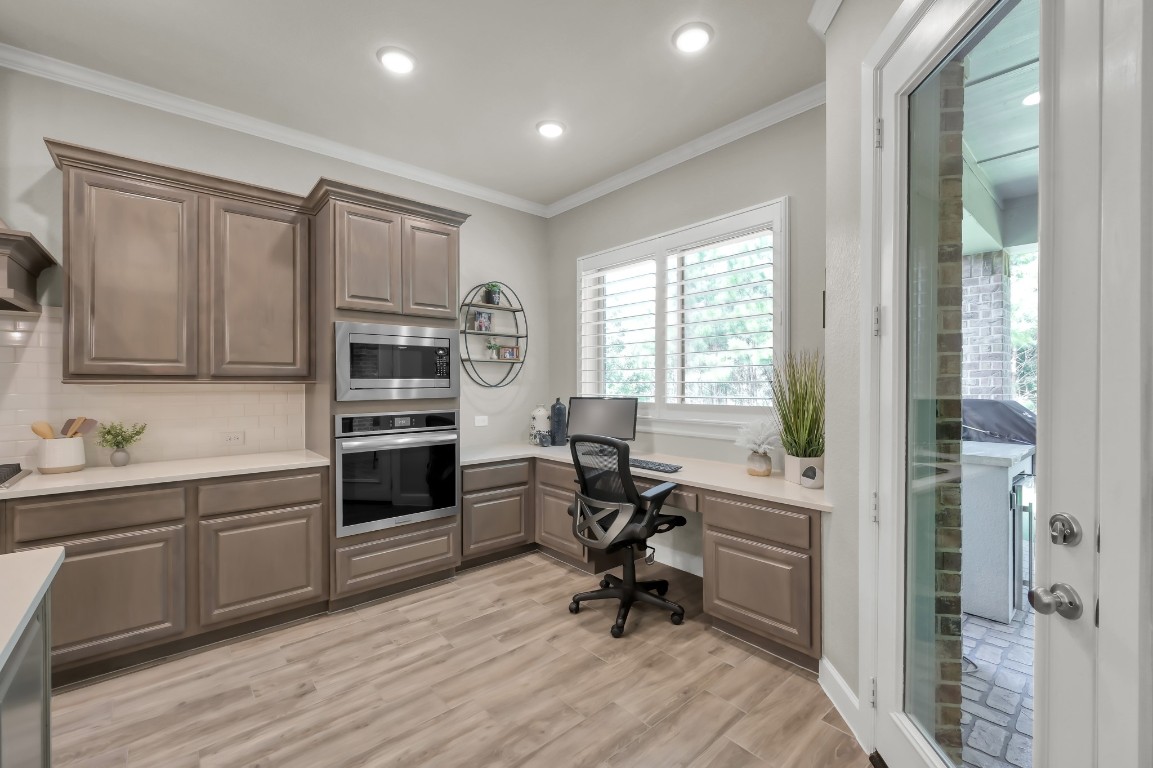 334 Torrey Bloom Loop Conroe, TX 77304 - Photo 16 of 46 Thoughtfully designed kitchen workspace with built-in desk, ample cabinetry, and convenient access to the covered patio—perfect for work or everyday organization.