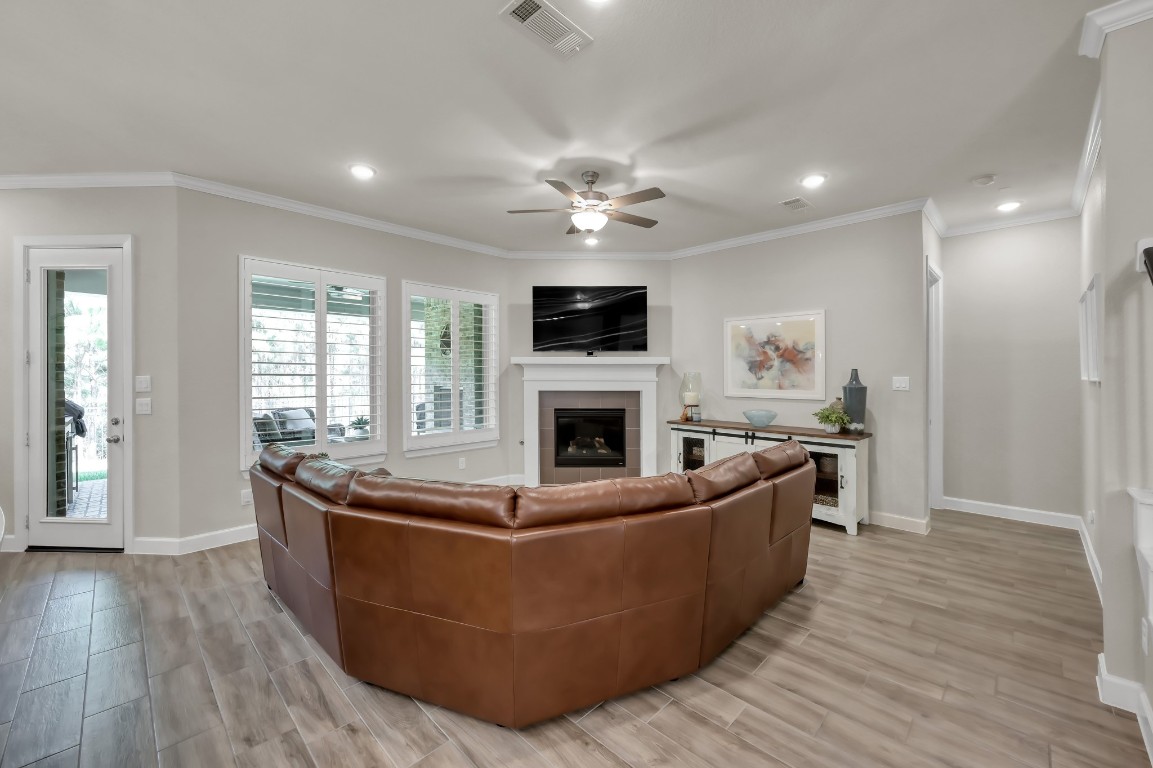 334 Torrey Bloom Loop Conroe, TX 77304 - Photo 18 of 46 Spacious family room with abundant natural light, crown molding, and a cozy fireplace—perfect for relaxing or entertaining.