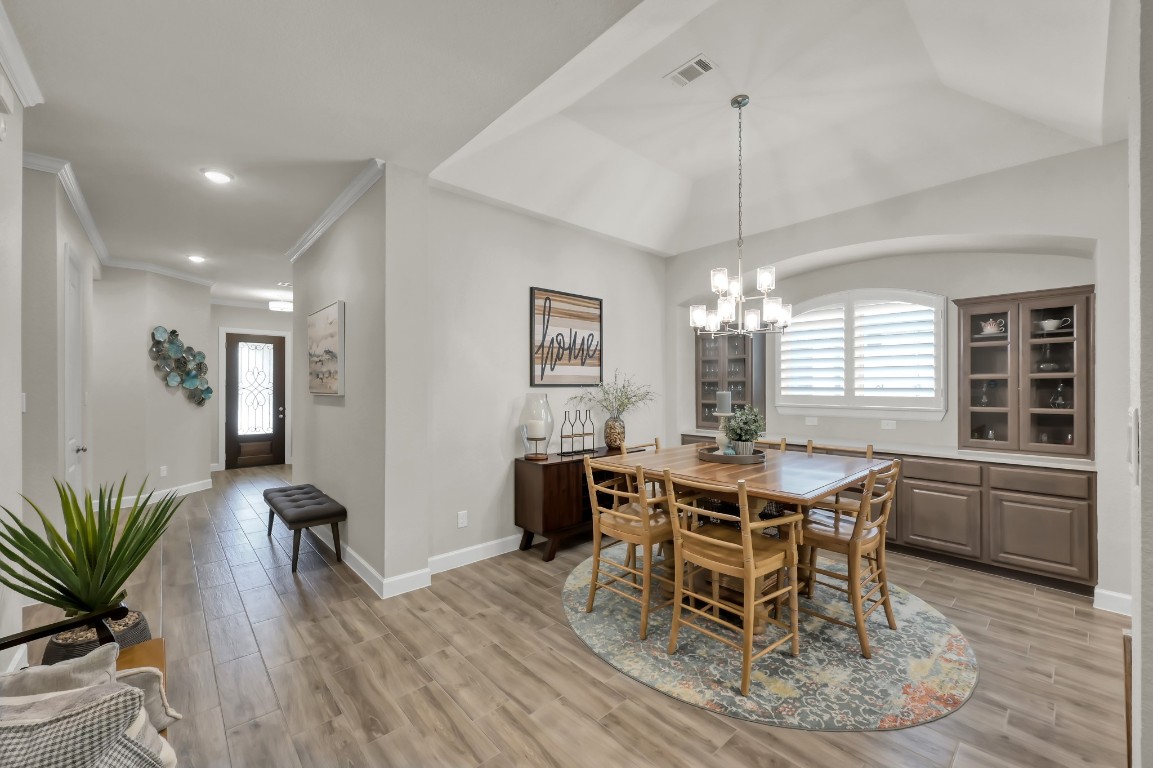 334 Torrey Bloom Loop Conroe, TX 77304 - Photo 9 of 46 Spacious dining area with tray ceiling, elegant lighting, and built-in cabinetry—perfect for gatherings and everyday entertaining.