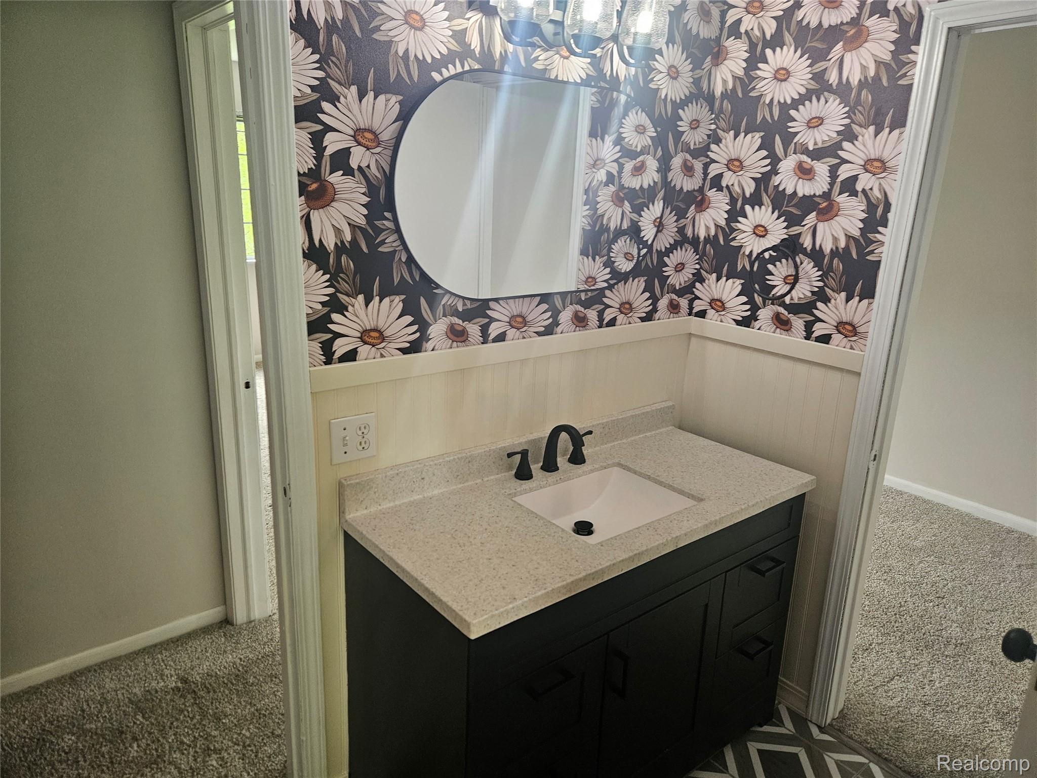 1210 Bay Ridge Drive Highland, MI 48356 - Photo 11 of 25 Bathroom featuring carpet flooring, vanity, wallpapered walls, and wainscoting