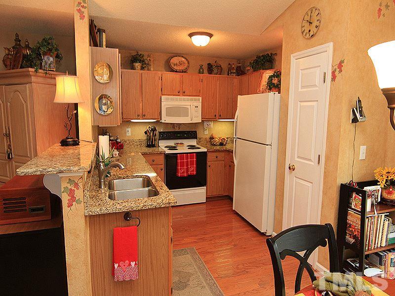 5121 Silverdene Street Raleigh, NC 27616 - Photo 5 of 12 a kitchen with stainless steel appliances granite countertop a refrigerator a stove and a sink with wooden floor